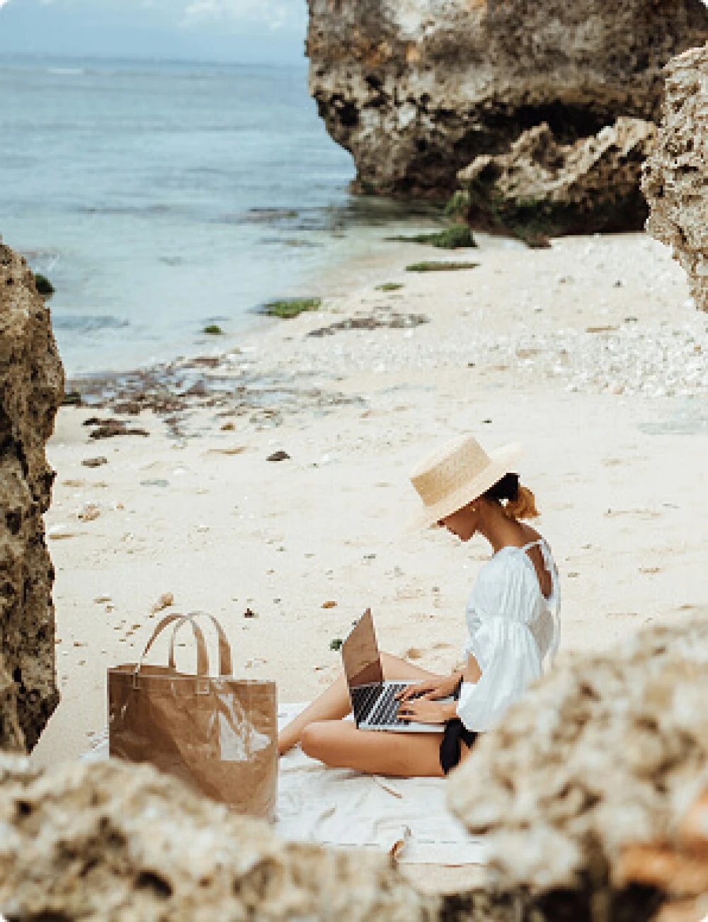 Woman sitting on a beach in Mallorca using laptop to search for property